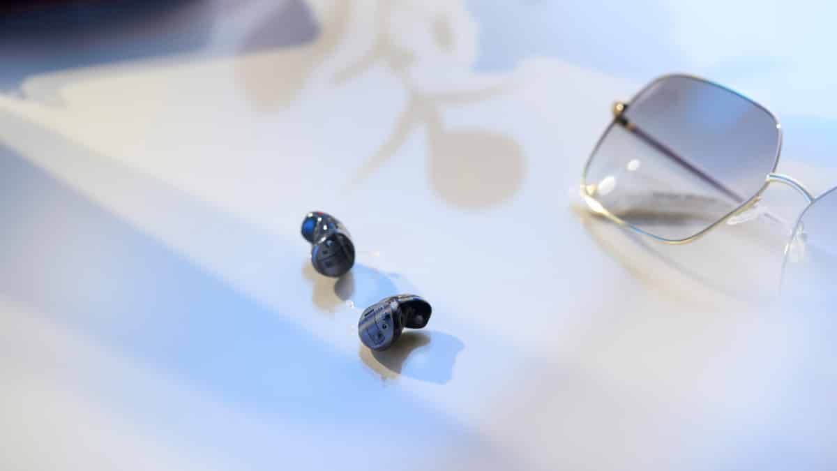 Winzige schwarze Savi CIC Hörgeräte neben einer Brille