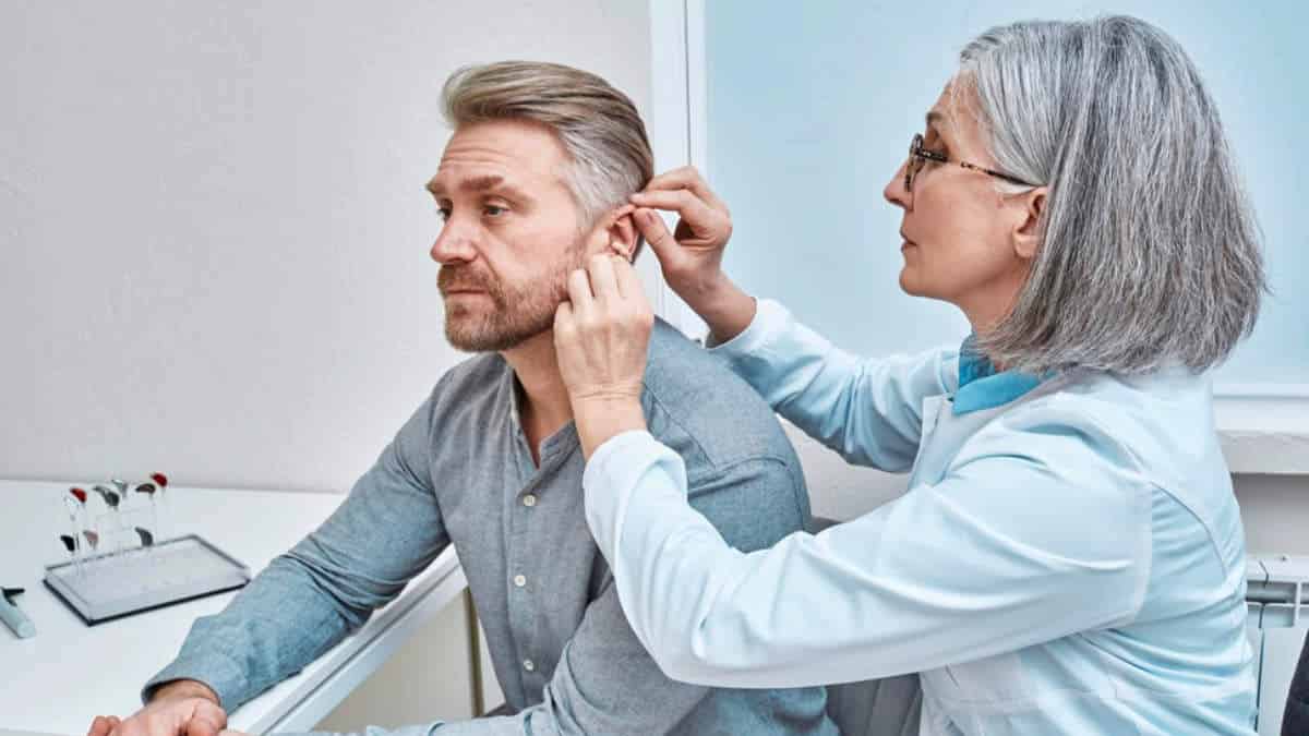 A female doctor fitting a male patients with a receiver-in-canal (RIC) on his left ear.
