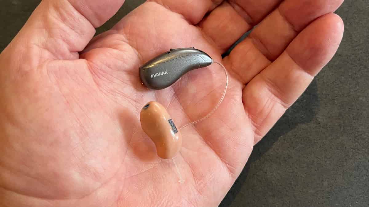 Infinio Ultra RIC hearing aid and custom earmold in palm of hand