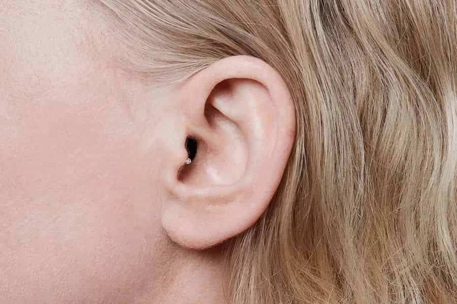 The only thing visible when wearing the Oticon Own IIC hearing aid is the small string used to pull it out of the ear.